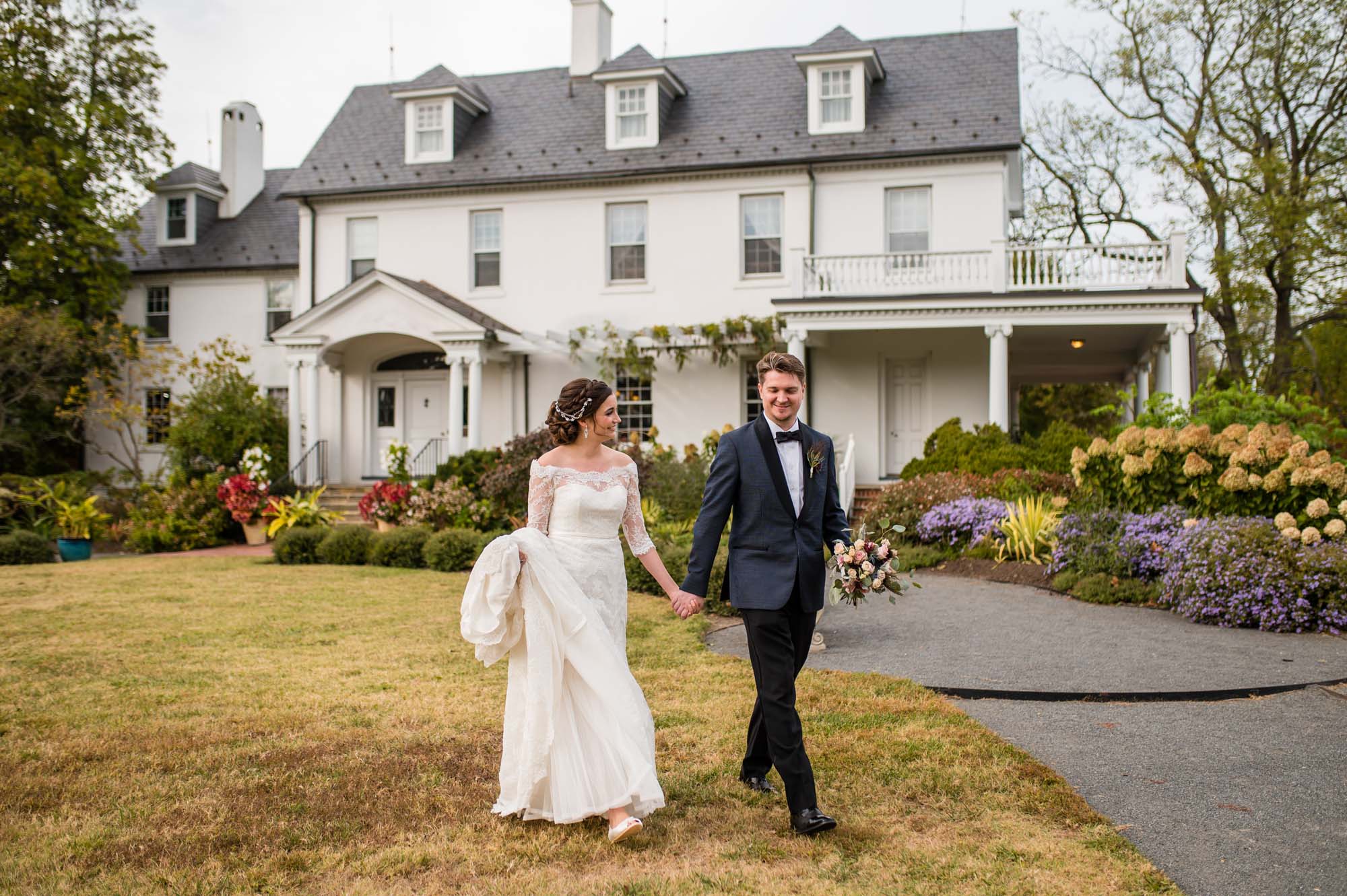 A couple walks out front of River Farm on their wedding day.